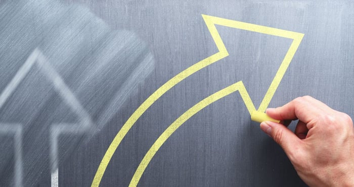 Person drawing an arrow with chalk on a chalkboard